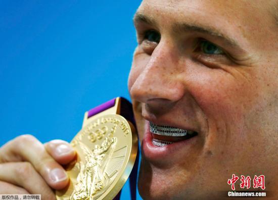 资料图：伦敦奥运游泳赛场，男混400米冠军罗切特带着钻石牙套试图咬金牌。